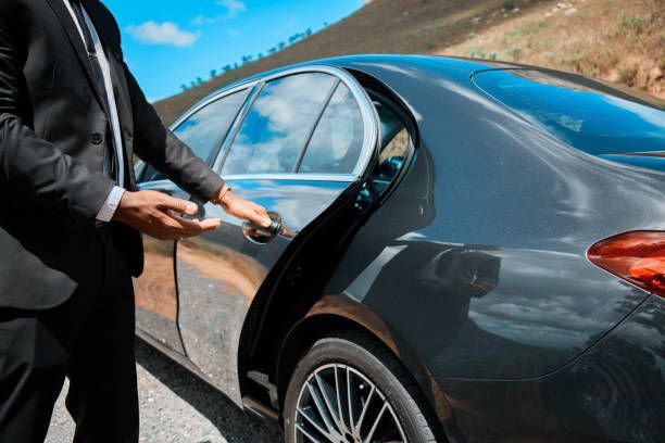 A man in a suit is opening the door of a car.