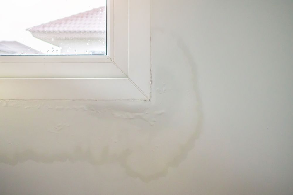 A close up of a window with water stains on the wall.