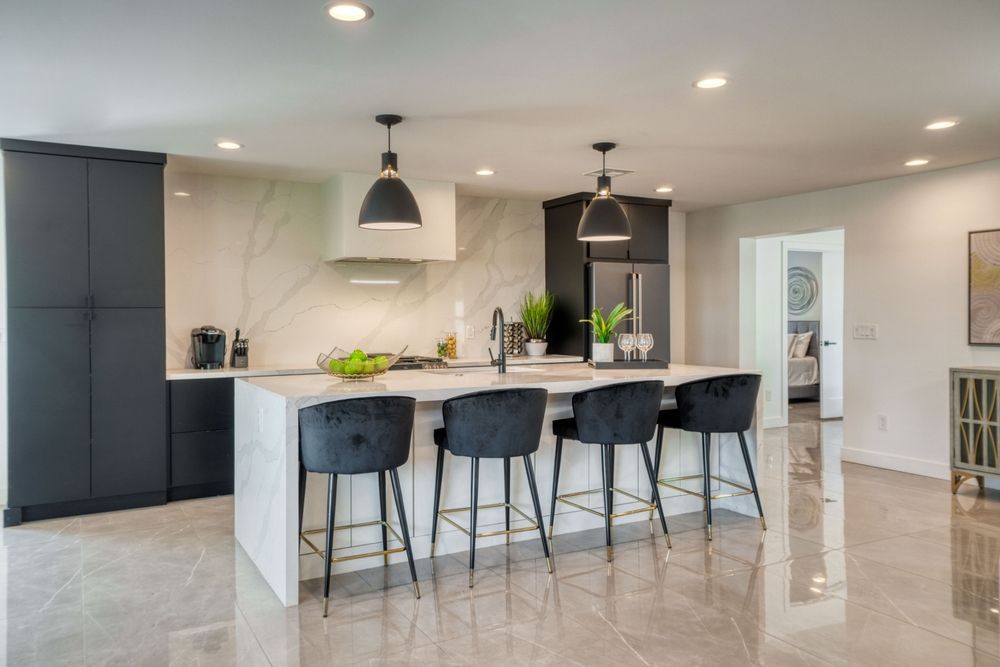 A kitchen with a large island and black chairs.