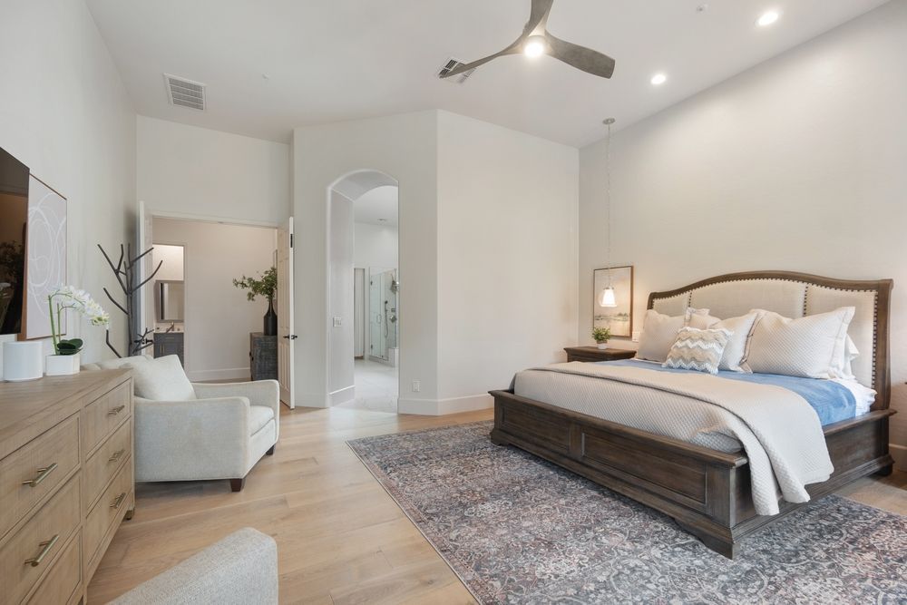 A bedroom with a large bed and a ceiling fan.