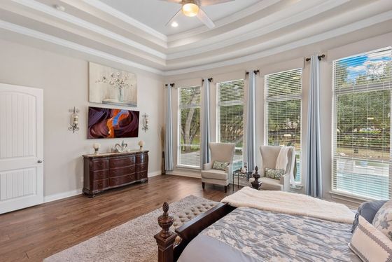 A bedroom with a bed , chairs , a dresser and a ceiling fan.