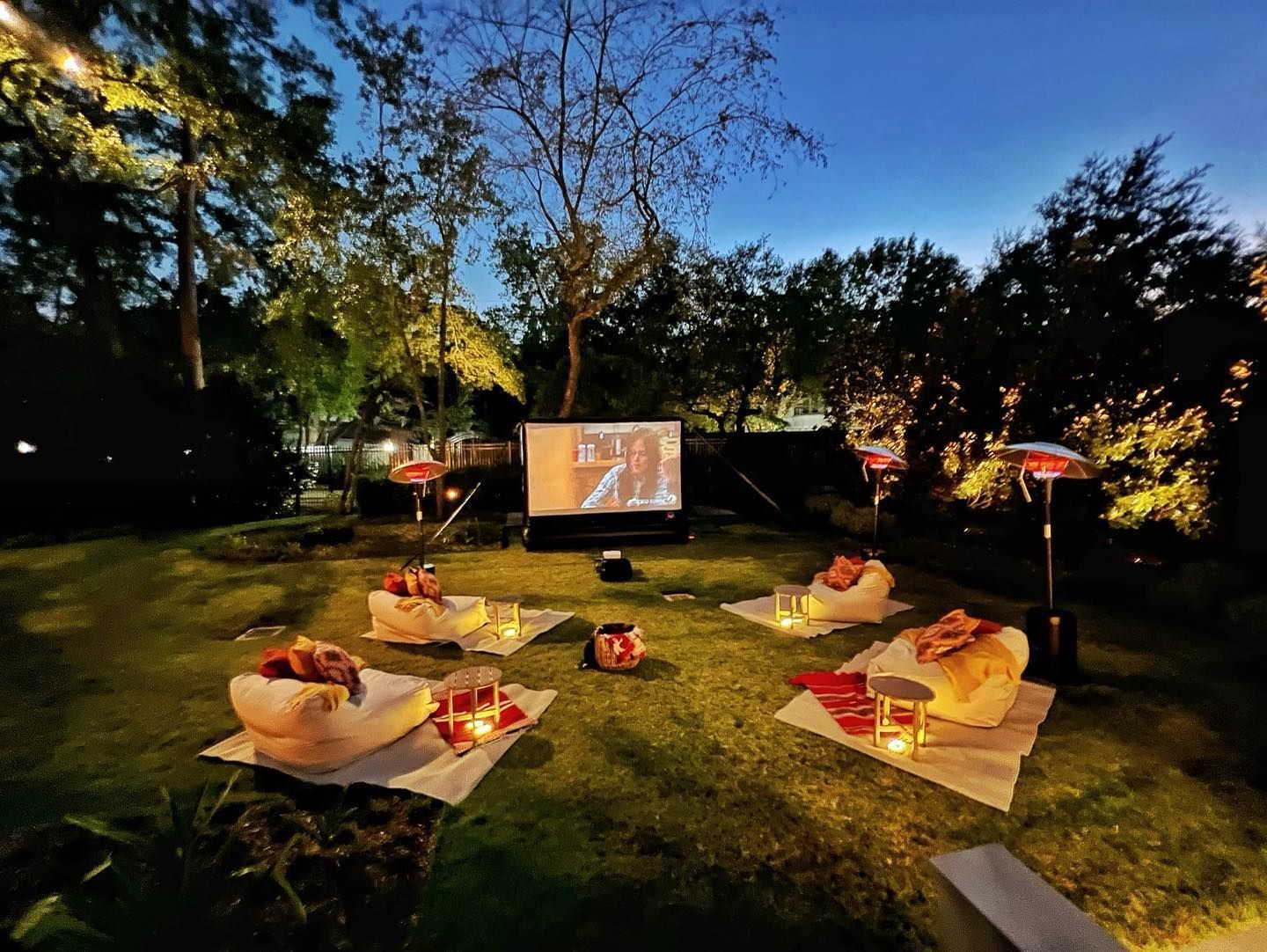 A projector screen in a backyard shows a movie