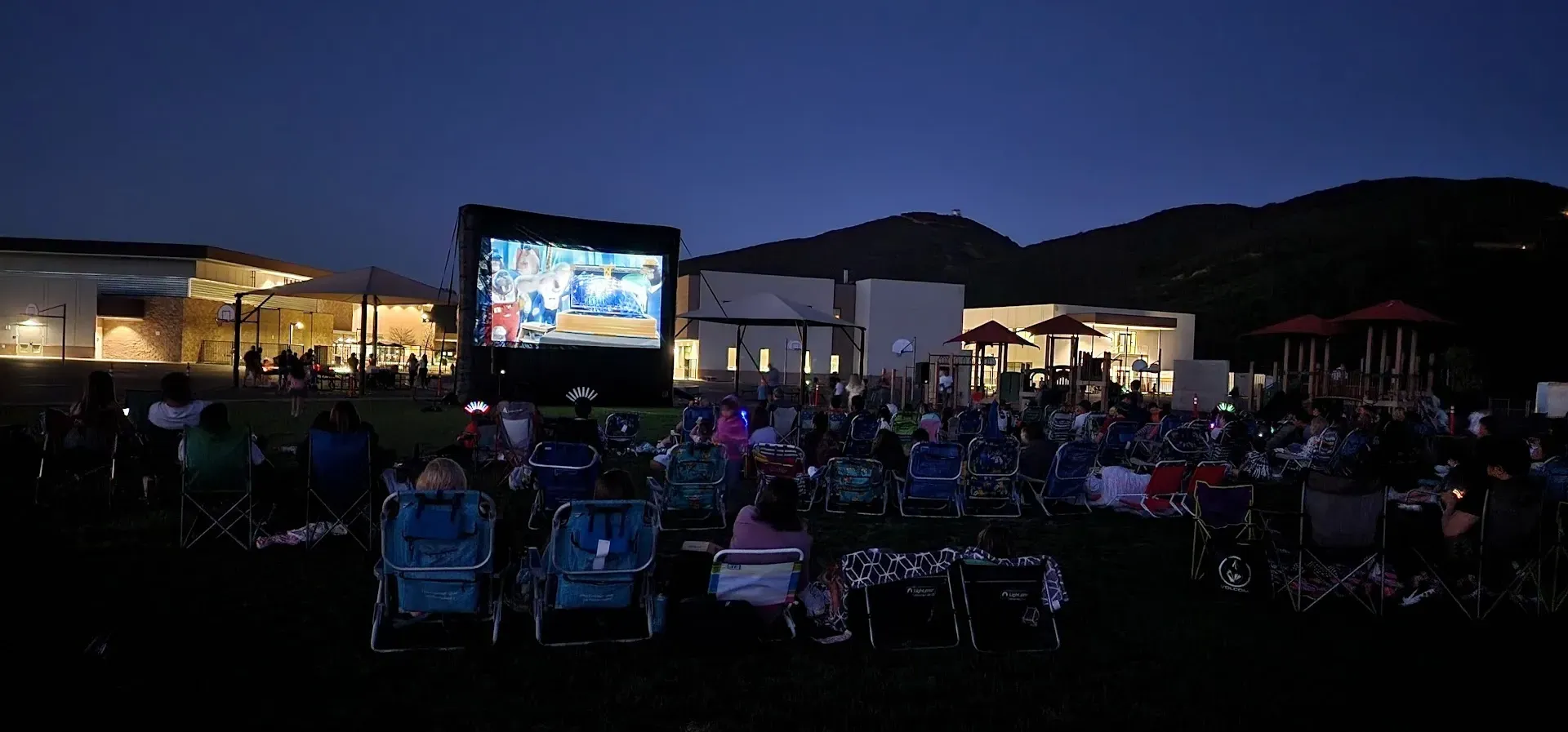 A crowd of people watching a movie on a large screen