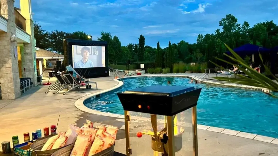A large screen is sitting next to a swimming pool.