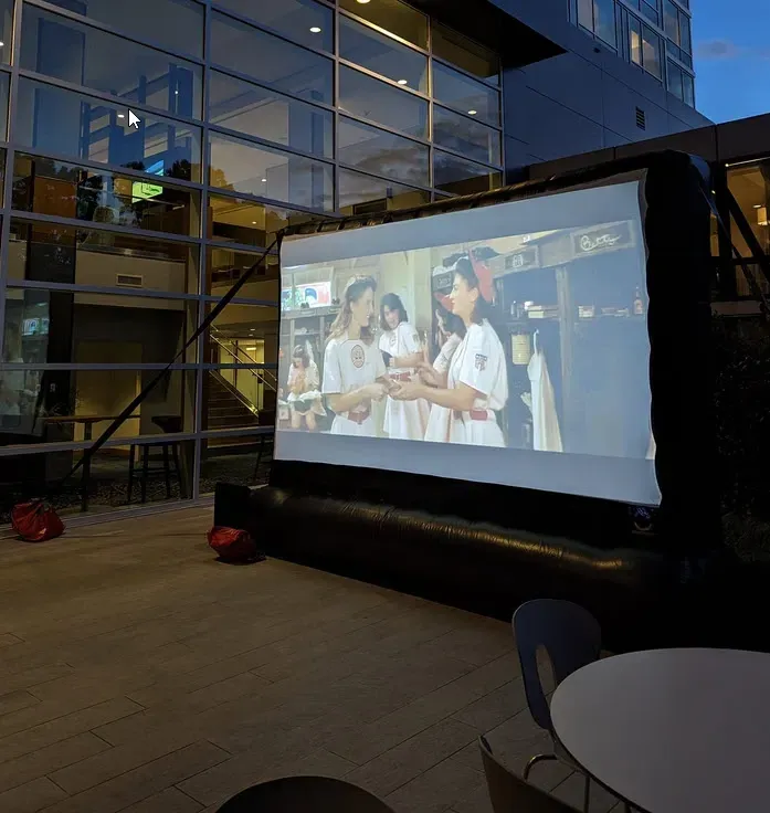 A large screen shows a group of people standing in front of a building