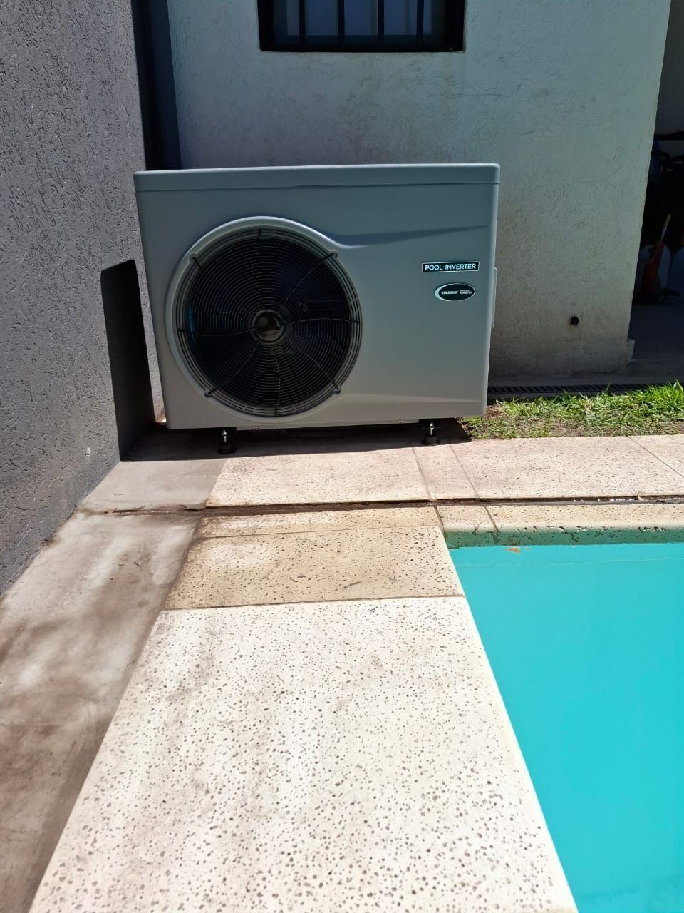 Un gran aparato de aire acondicionado está situado junto a una piscina.