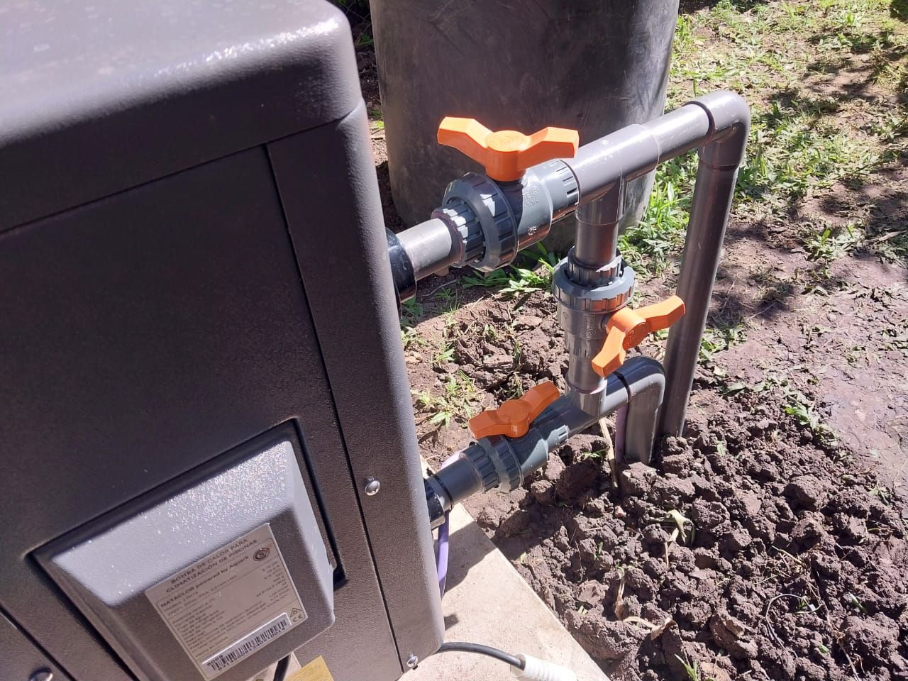 Una válvula naranja está conectada a una tubería al lado de una caja.