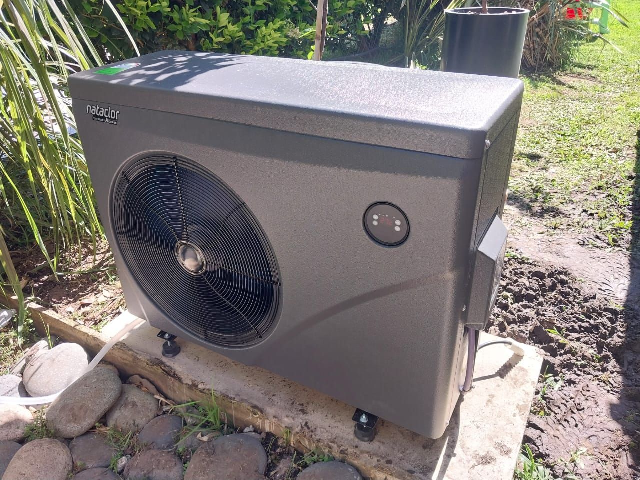 Un acondicionador de aire negro está situado encima de una losa de hormigón.