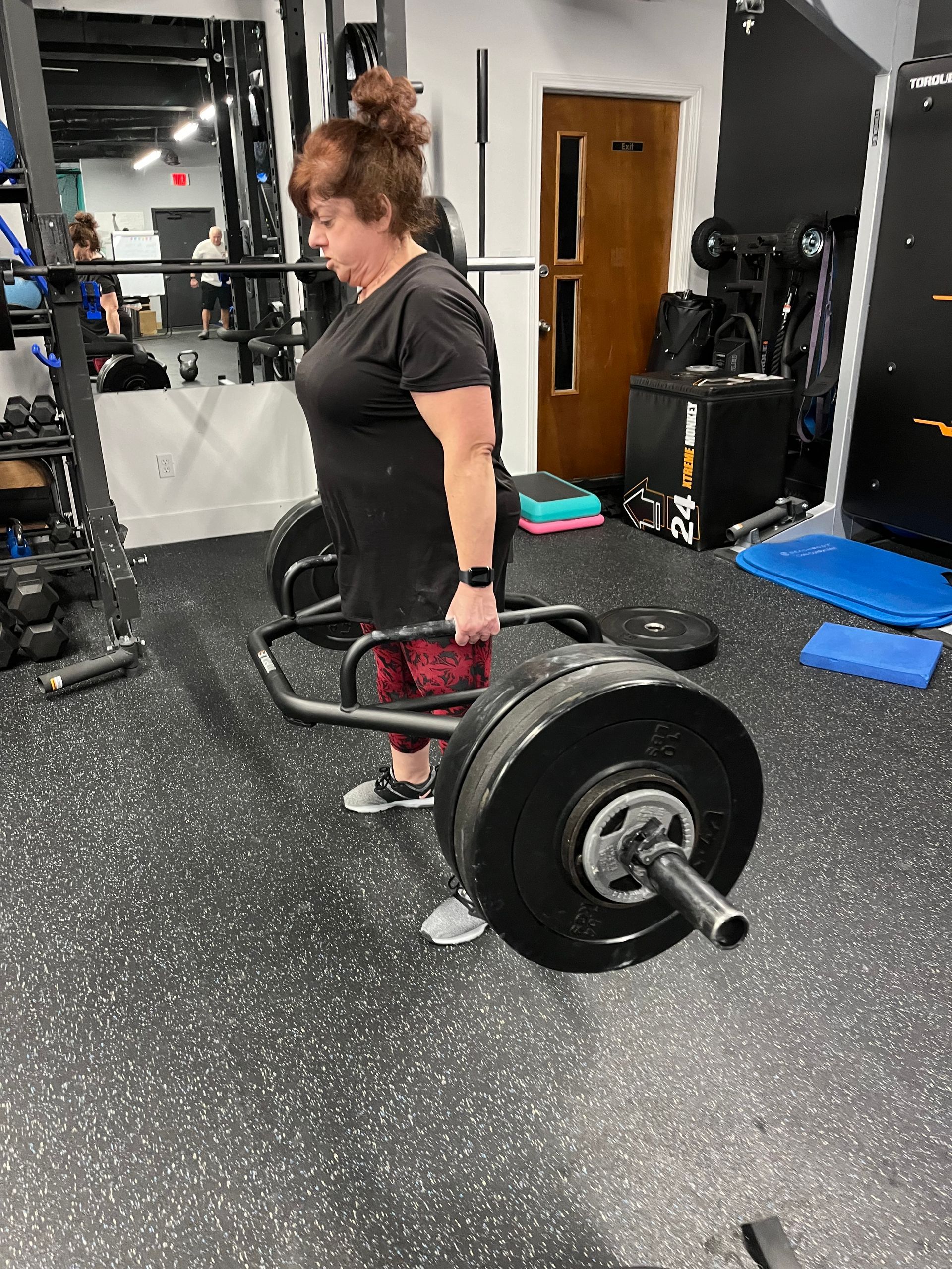 A woman is lifting a barbell in a gym.