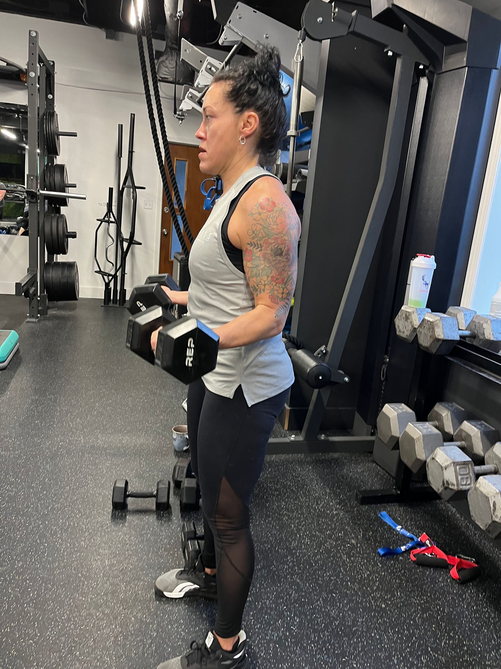 A woman is holding a dumbbell in a gym.