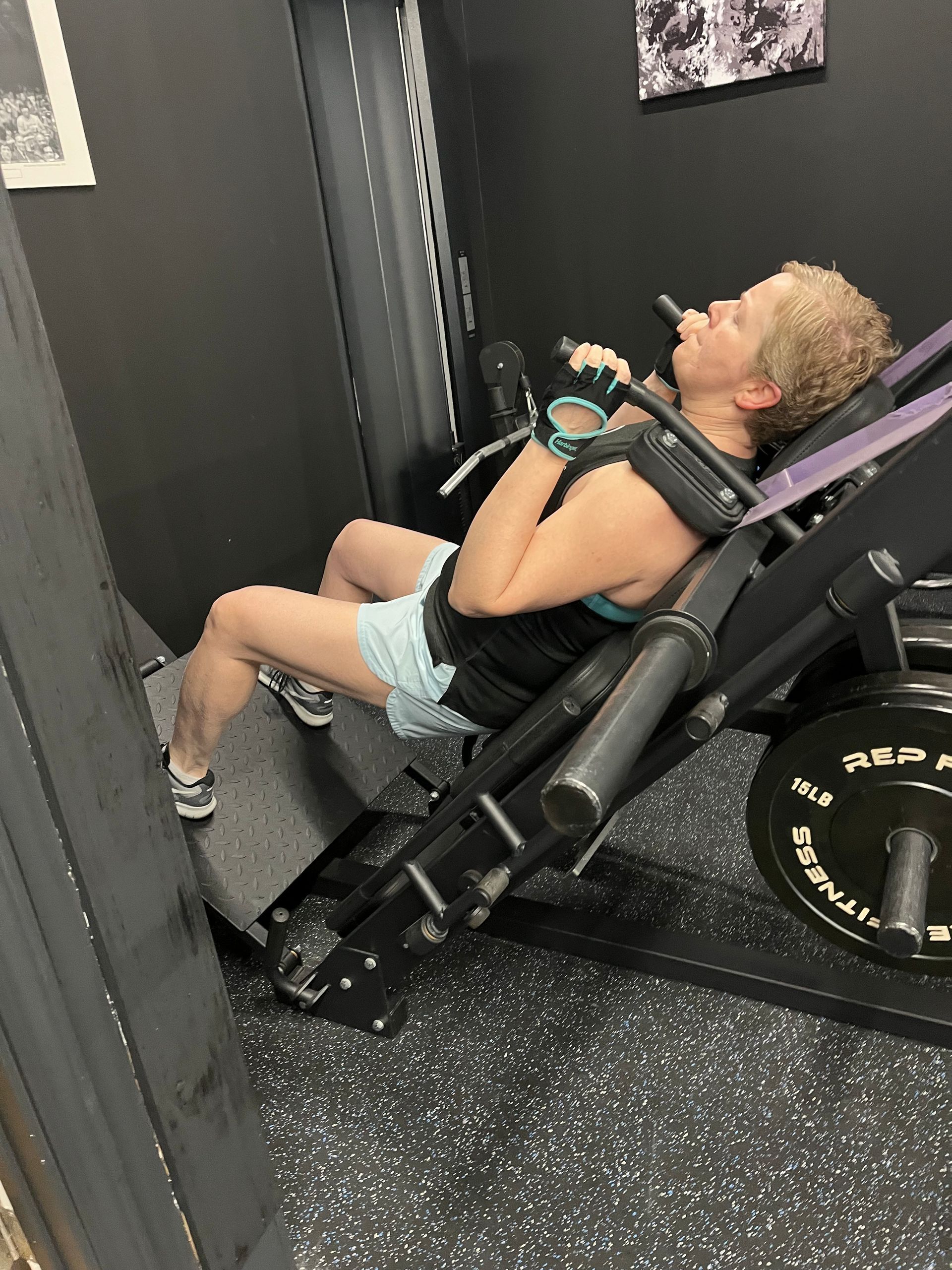 A woman is sitting on a machine in a gym.