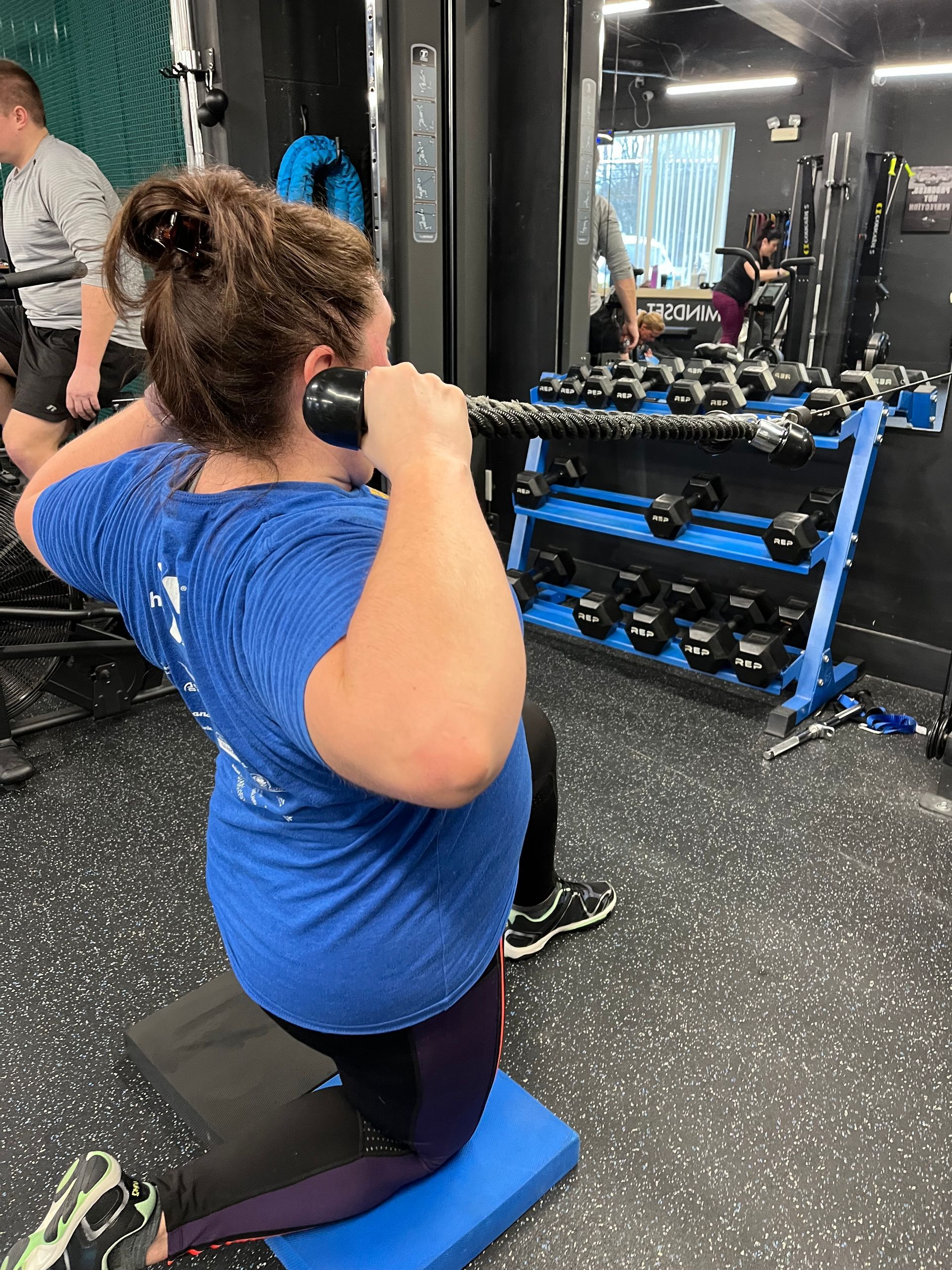 A woman is squatting with a barbell in a gym.