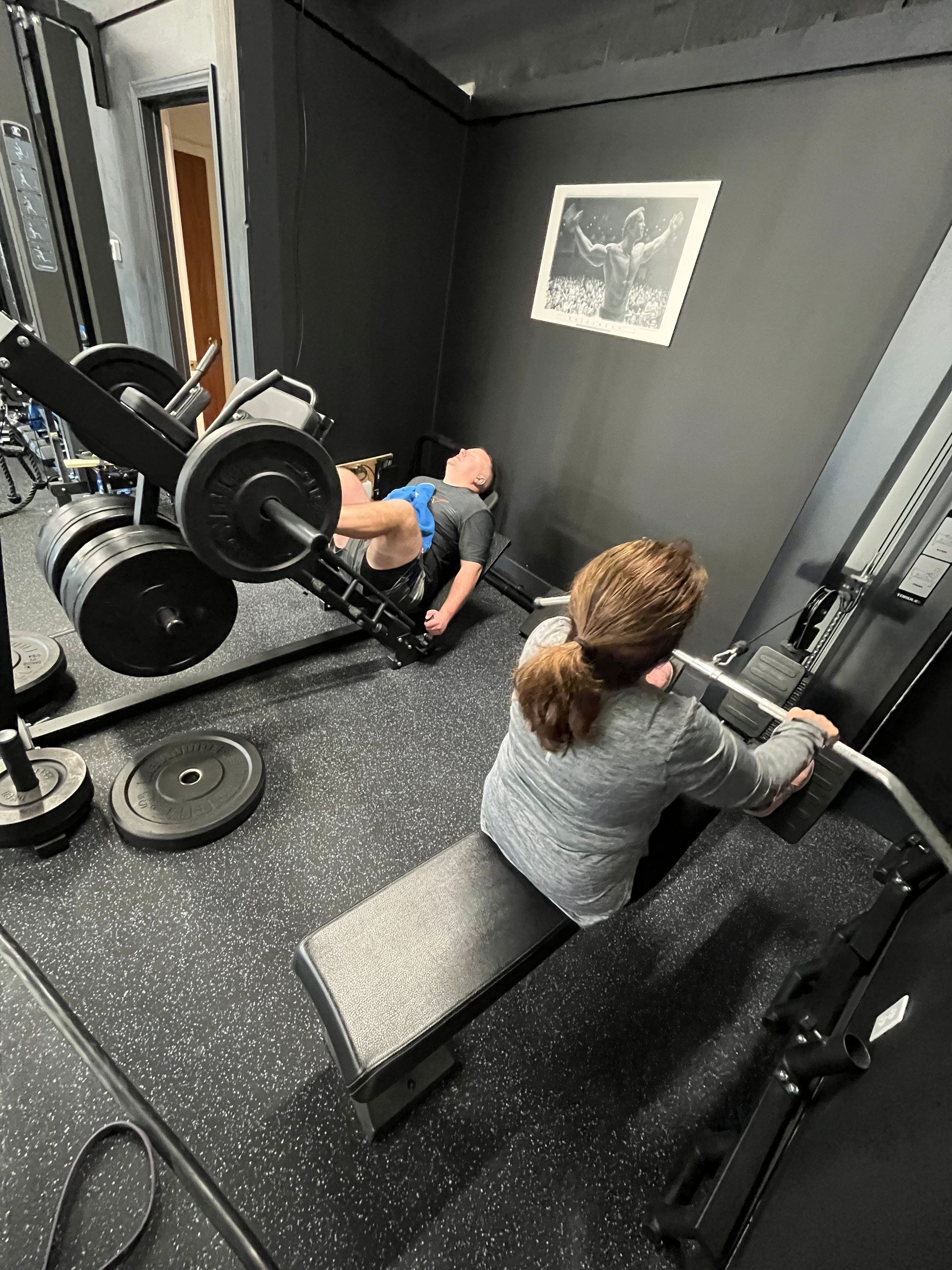 A woman is sitting on a bench in a gym holding a barbell.