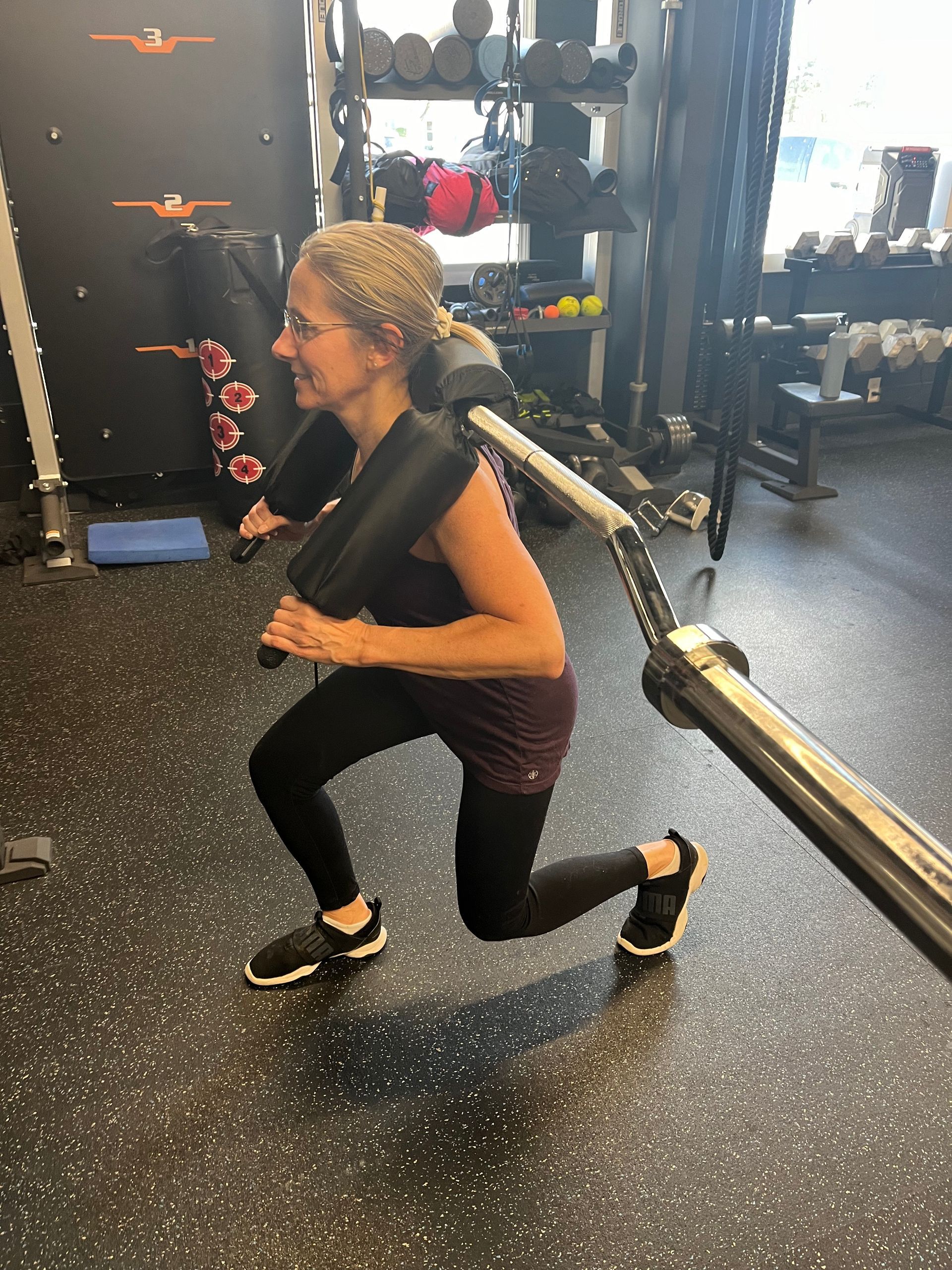 A woman is doing lunges on a machine in a gym.