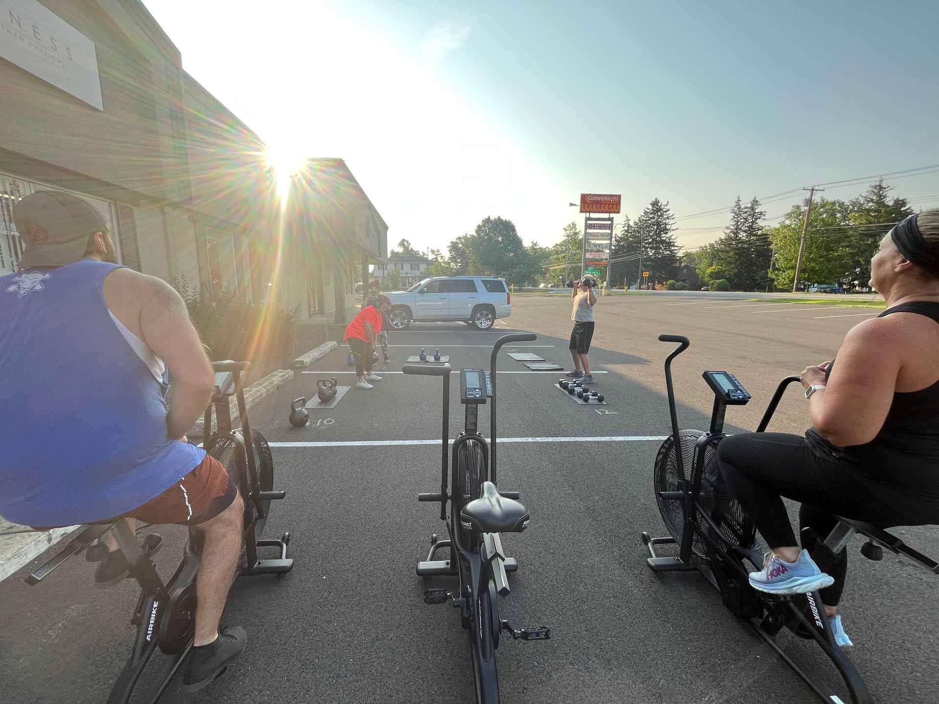 A group of people are riding exercise bikes in a parking lot