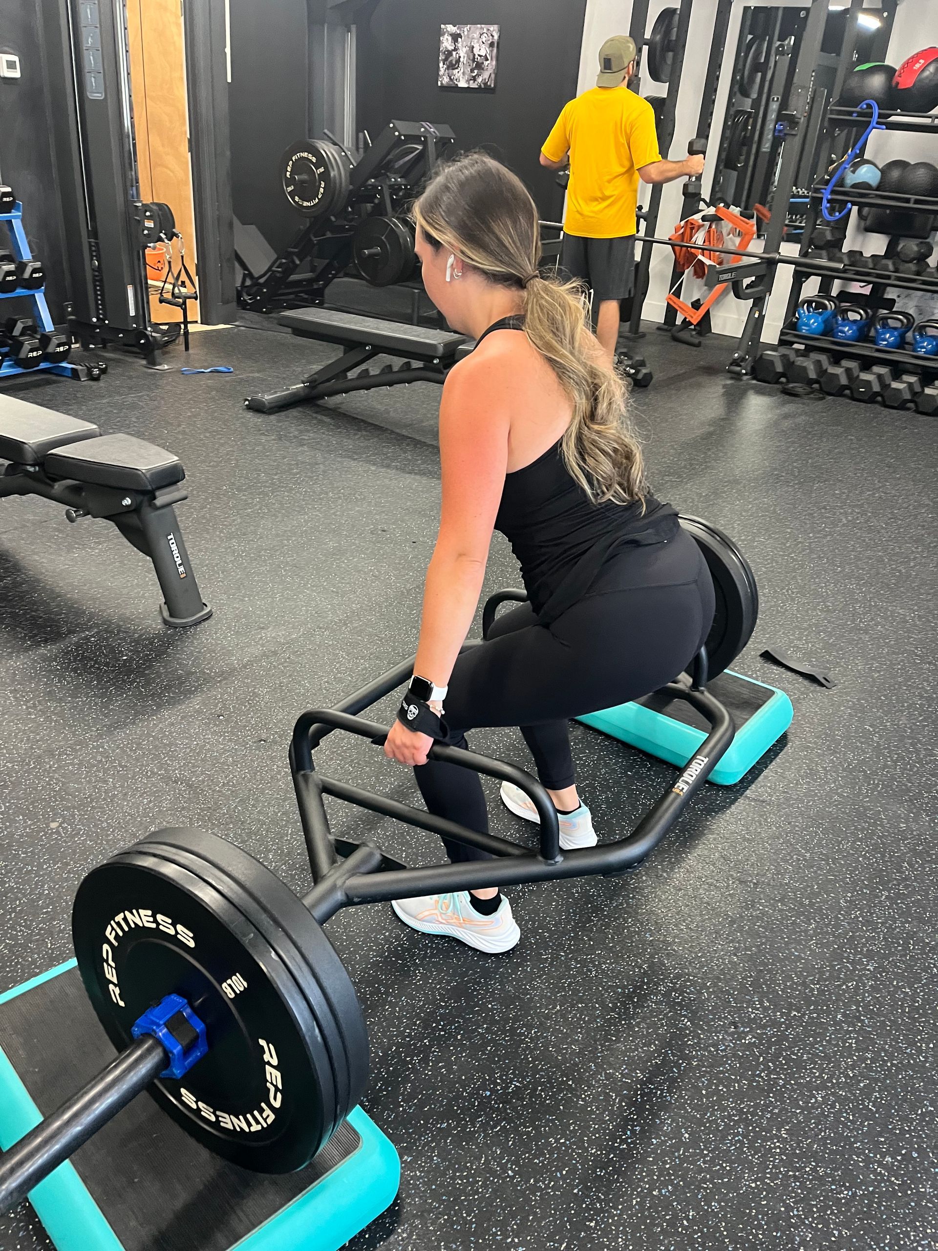 A woman is lifting a barbell in a gym.