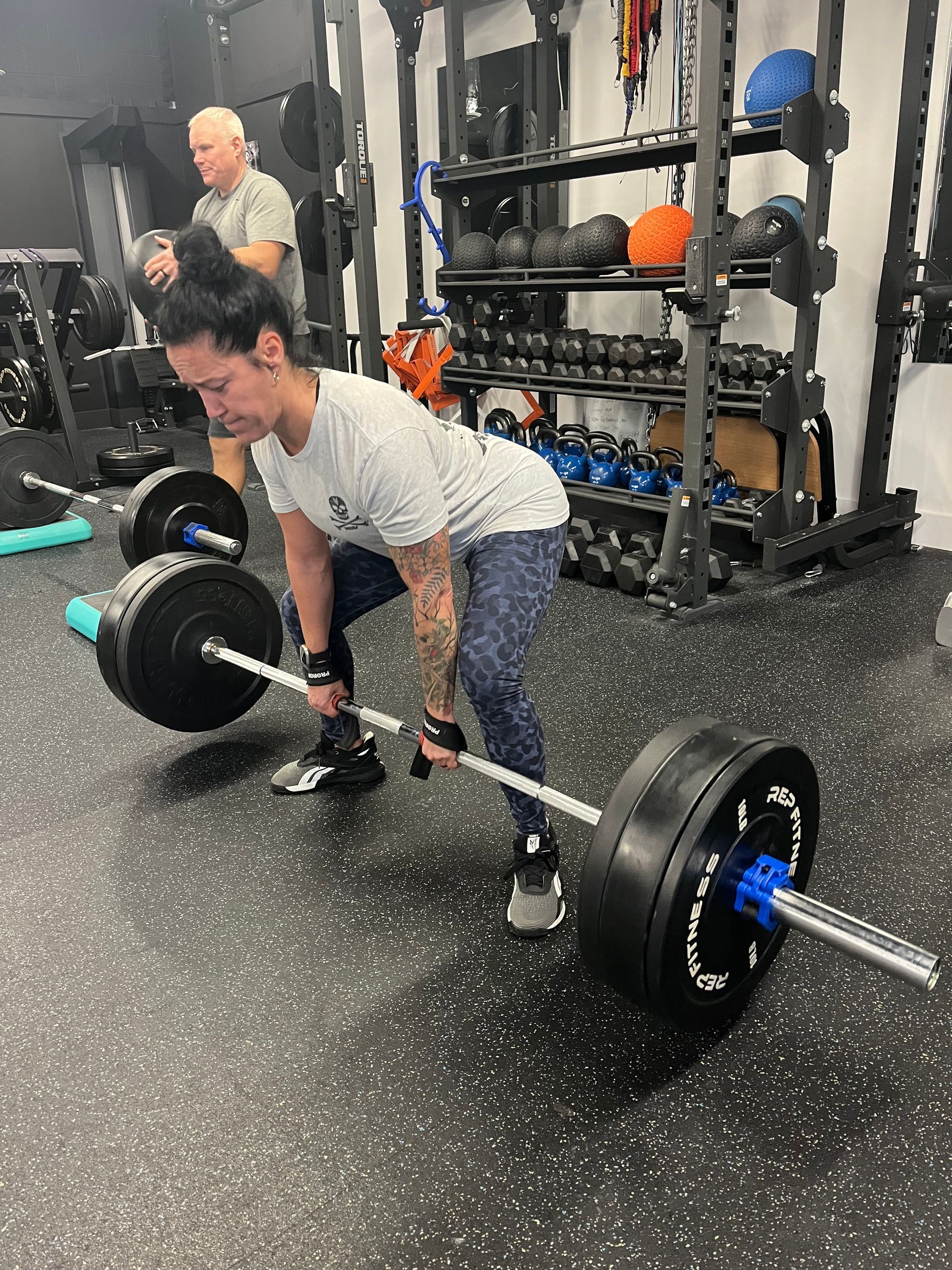 A woman is lifting a barbell in a gym.
