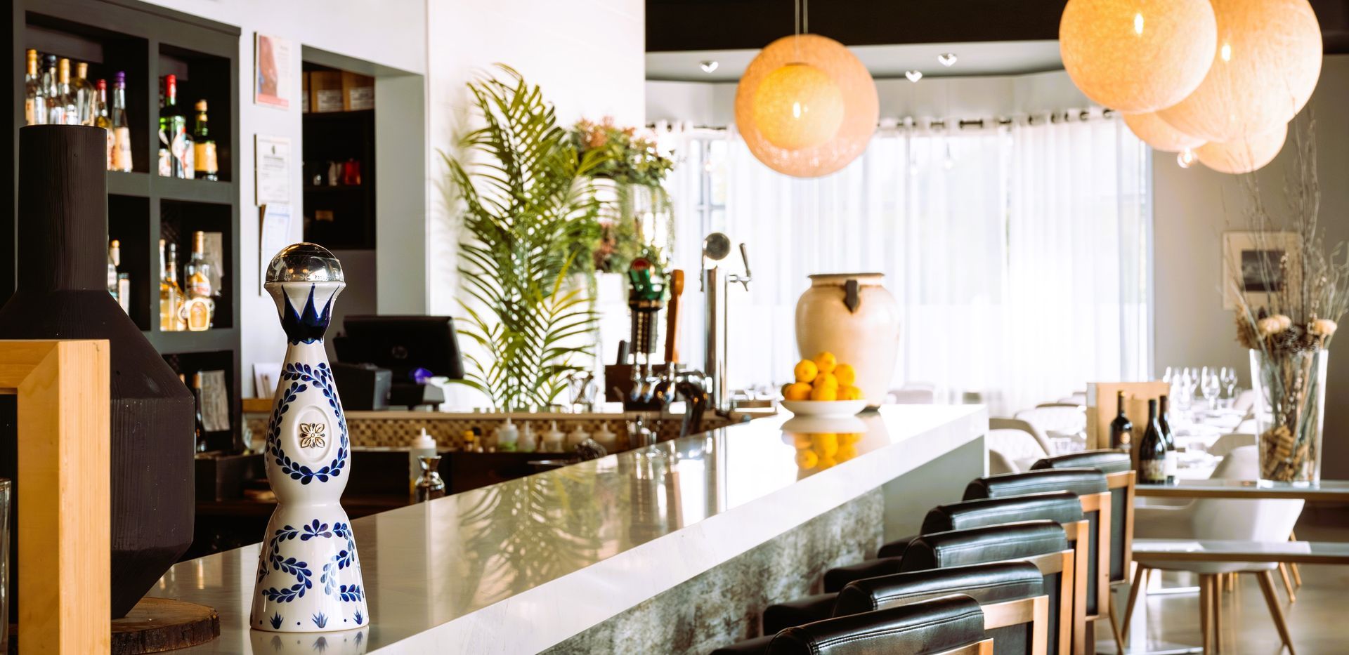 A bar in a restaurant with a blue and white vase on the counter.