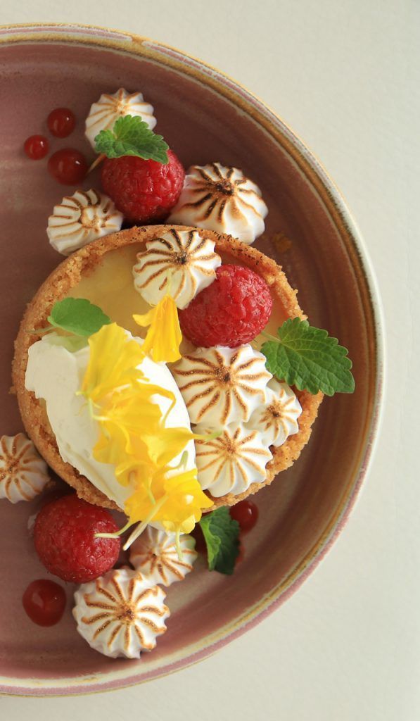 A close up of a dessert with strawberries and meringue on a plate.