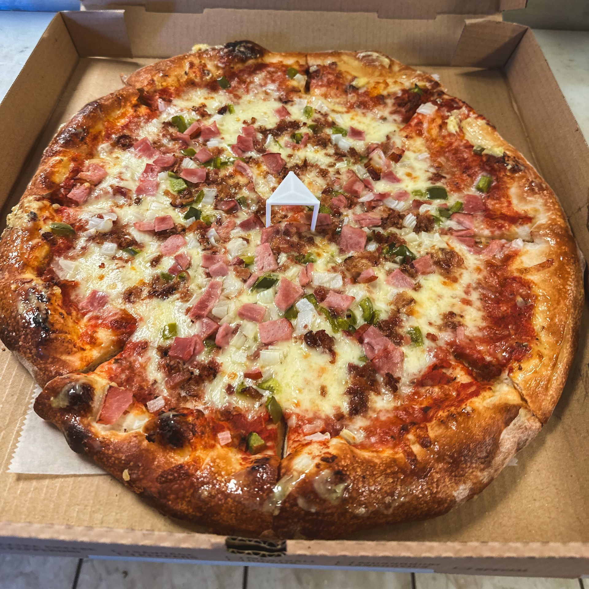 A pizza with pepperoni , olives , mushrooms and cheese is in a box.