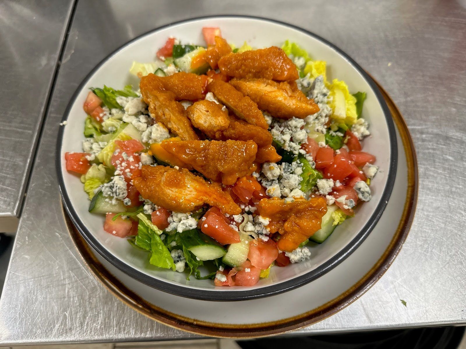 A salad with chicken and vegetables on a plate on a table.
