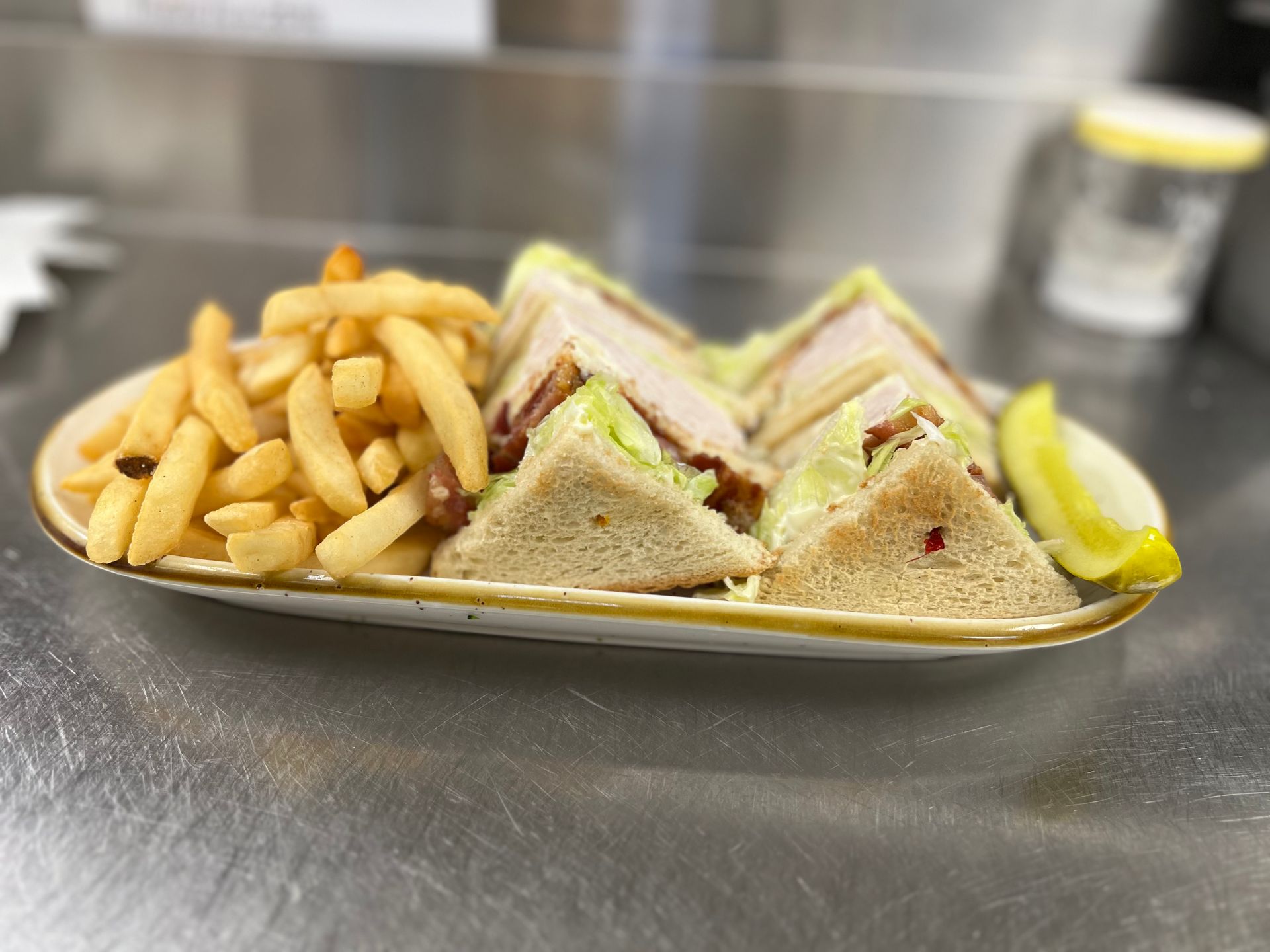 A sandwich and french fries on a plate on a table.