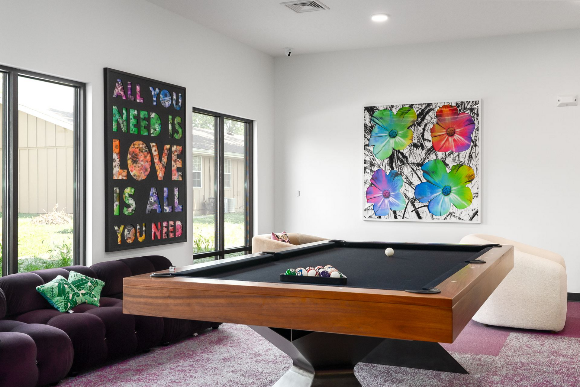 Pool table in a room with colorful art and a large couch.
