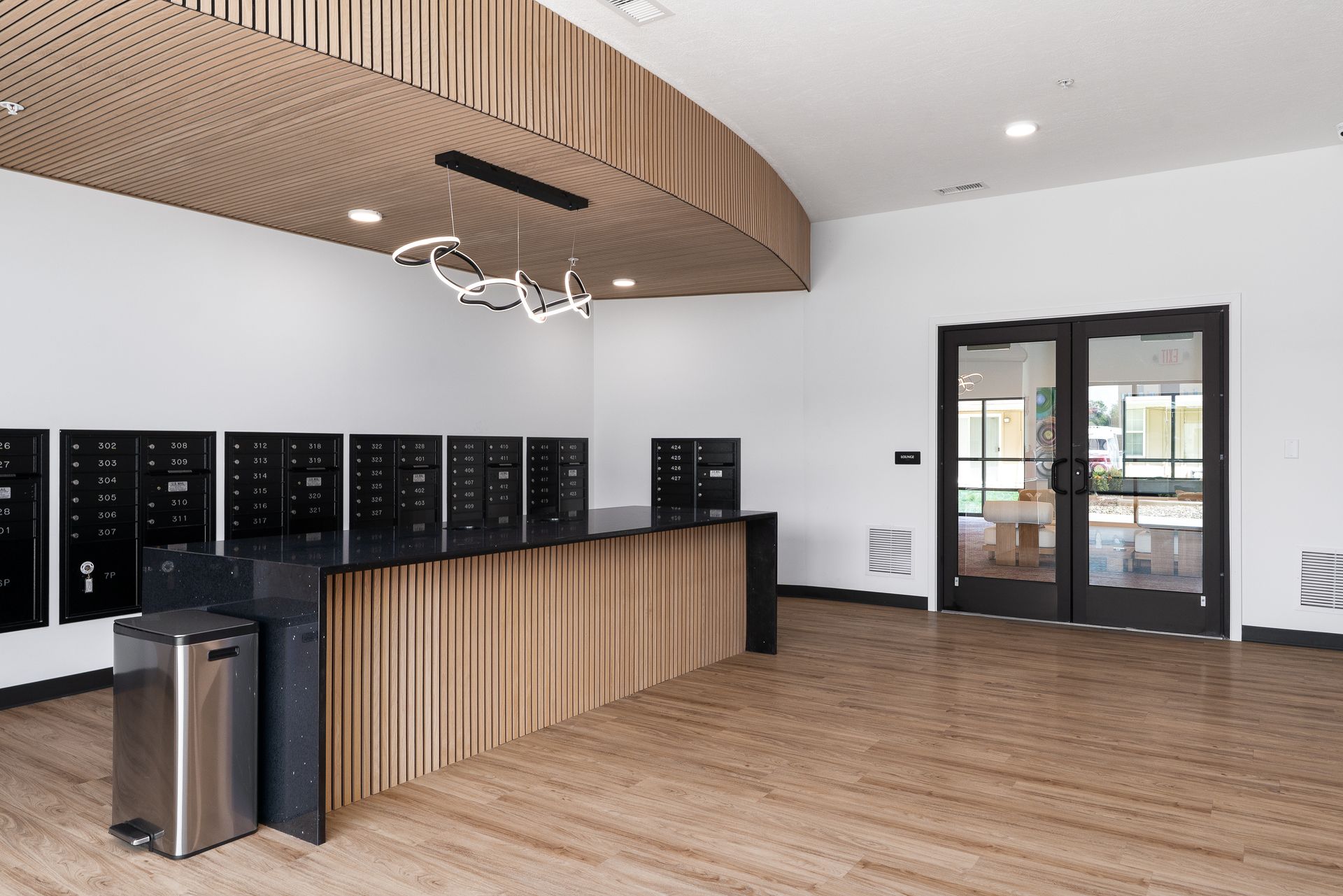 Apartment lobby with mailboxes, wooden accents, and double doors to the outside.