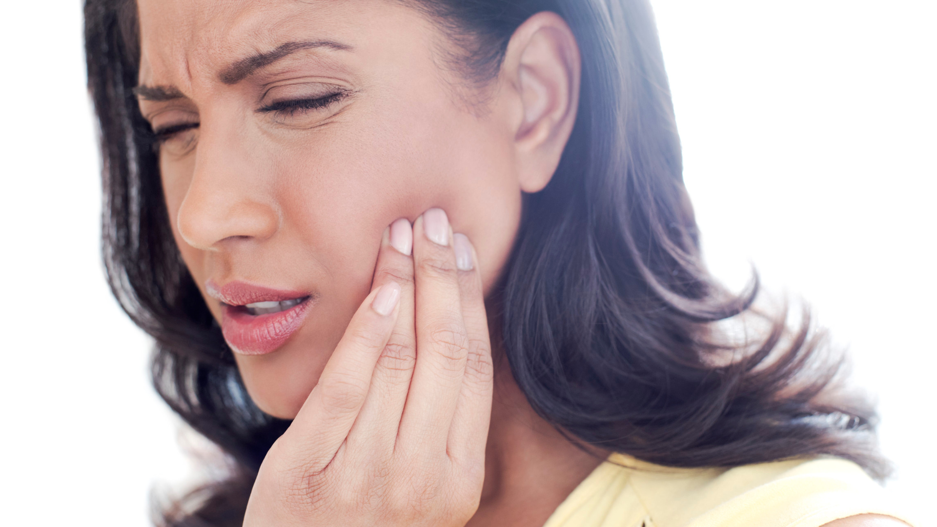 A woman is holding her face in pain because of a toothache.