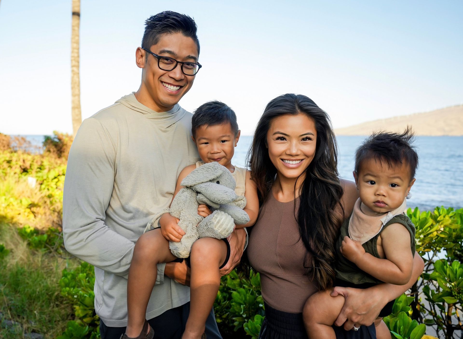 A family is posing for a picture in front of the ocean.