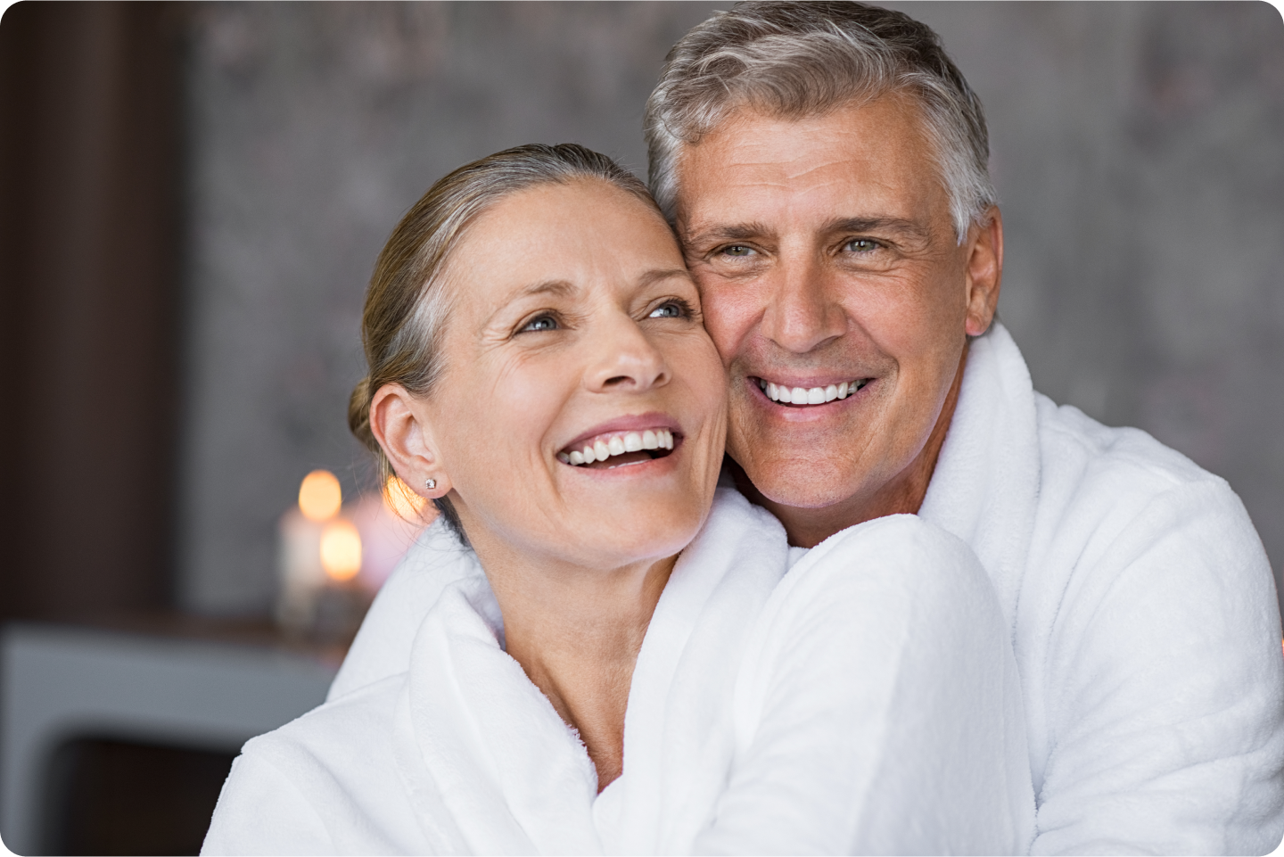 A man and a woman are hugging each other and smiling.