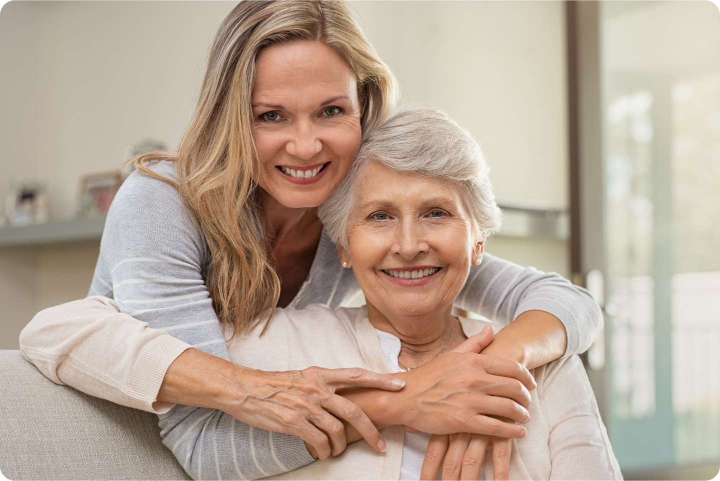 A young woman is hugging an older woman on a couch.