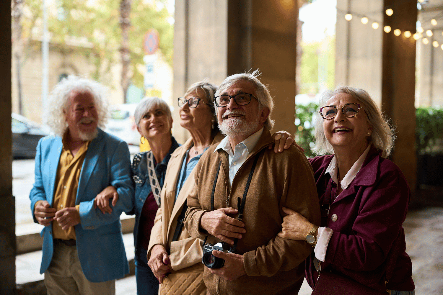 Group of smiling people standing together indoors near windows and string lights