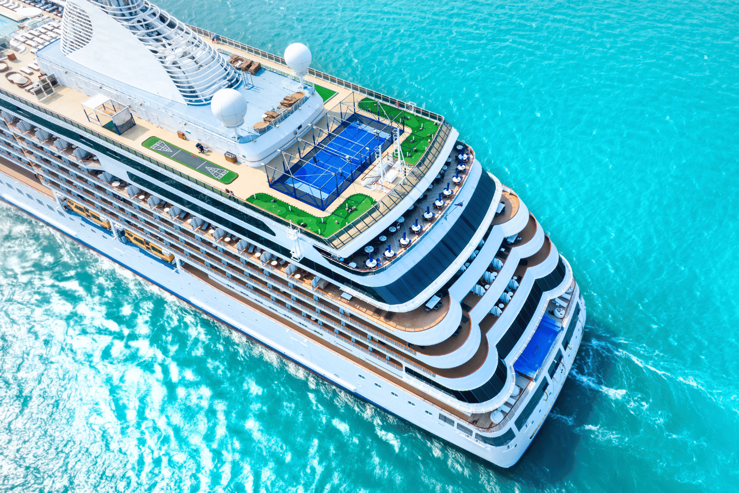 Cruise ship on turquoise water, top view. Pools on deck, sunny day.
