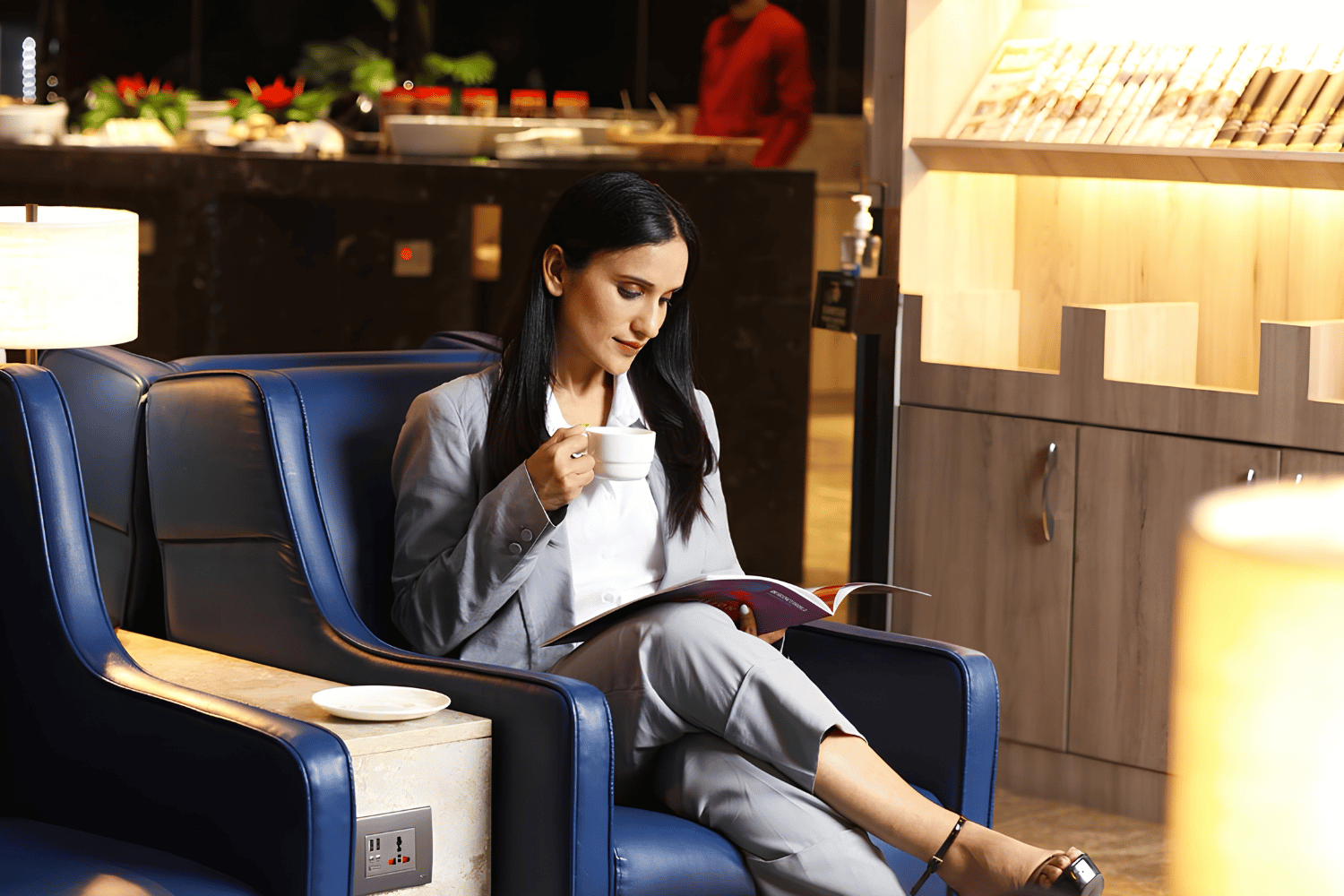 Woman reading on a blue lounge chair in a hotel lobby