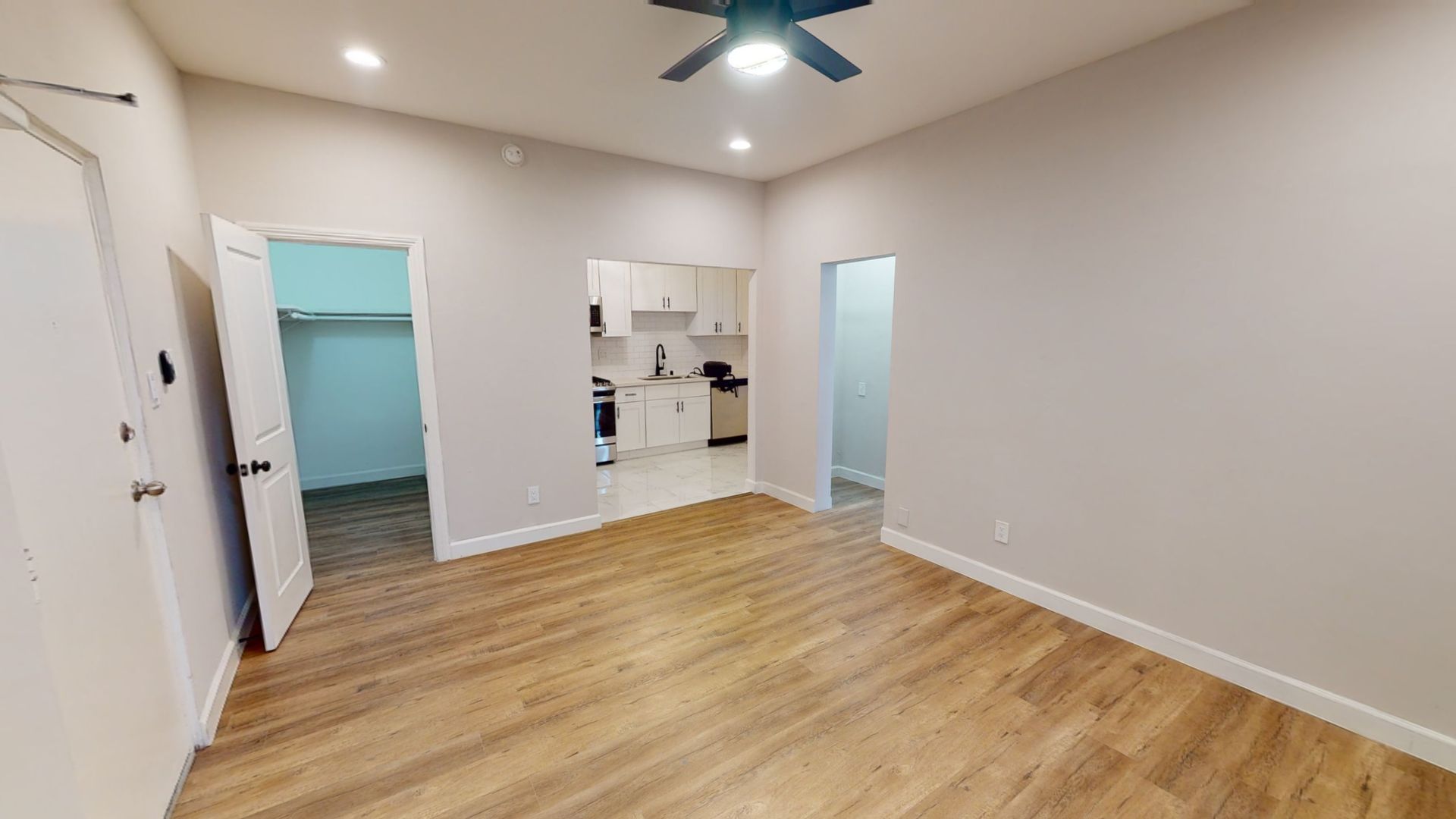 Interior view of an apartment with hardwood floors, doorways to closet, kitchen, and bathroom.