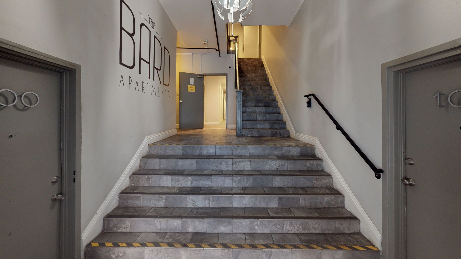 Hallway with gray stairs, doors on sides, and graffiti 