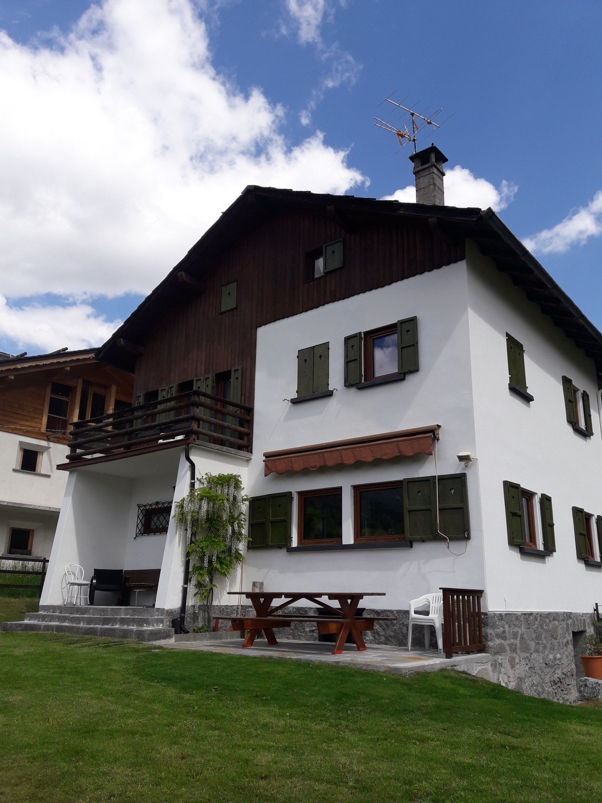 Una casa bianca con il tetto di legno e le persiane verdi