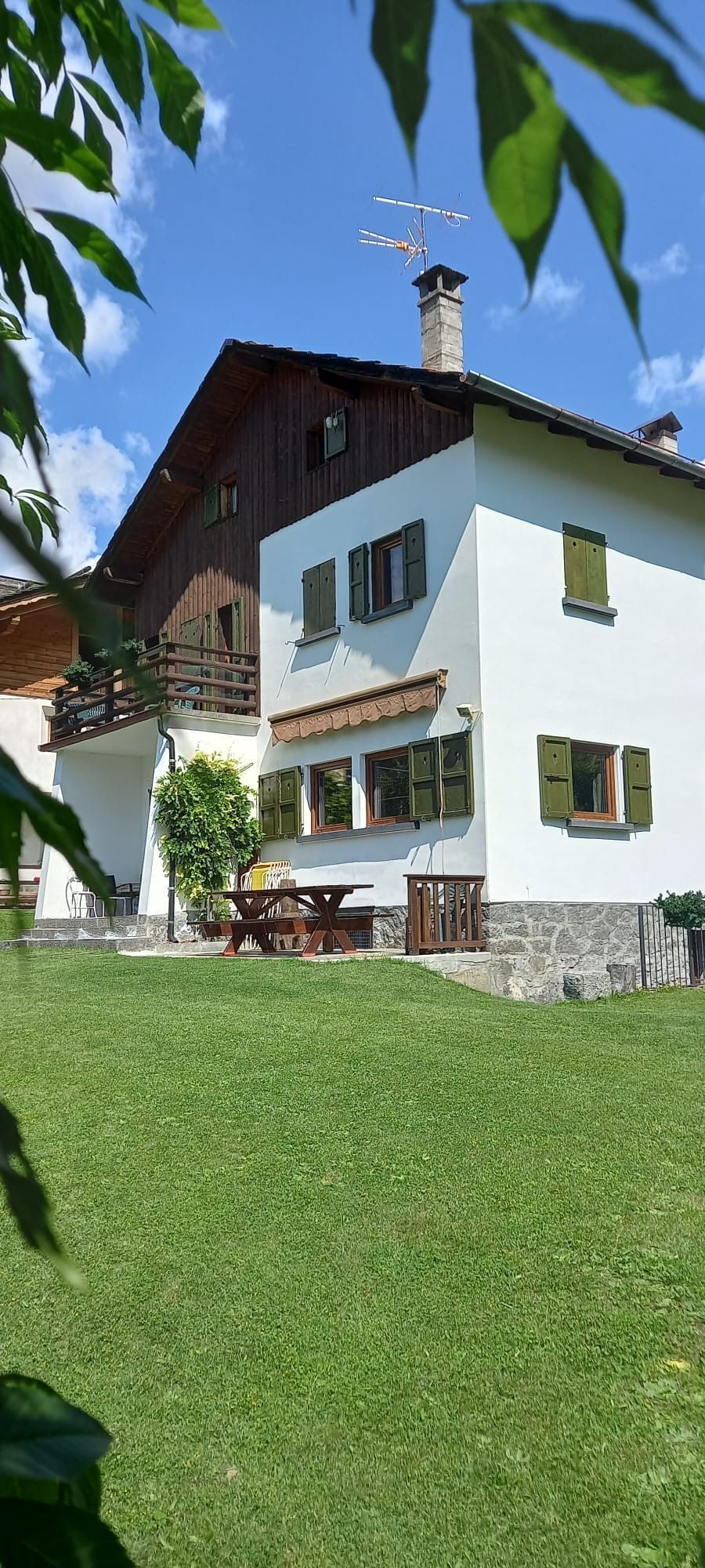 Una grande casa bianca con il tetto di legno e un grande prato davanti.