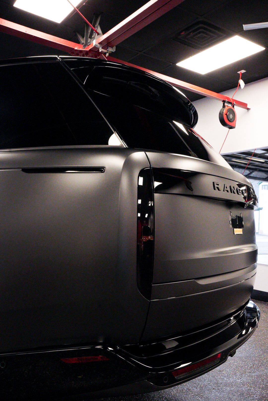 Dark gray Range Rover SUV rear view, black trim, inside a garage.