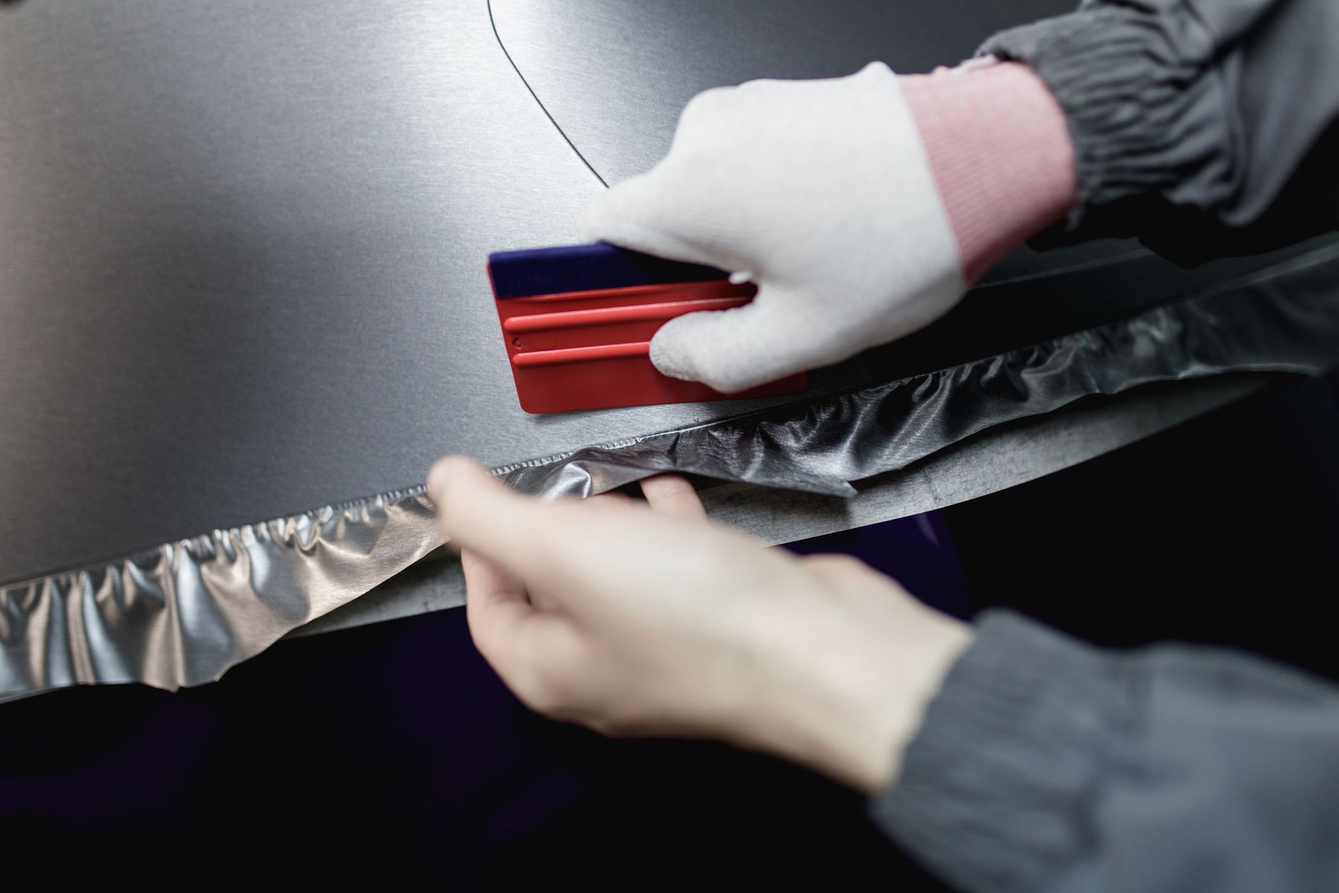 A person is wrapping a car with aluminum foil.
