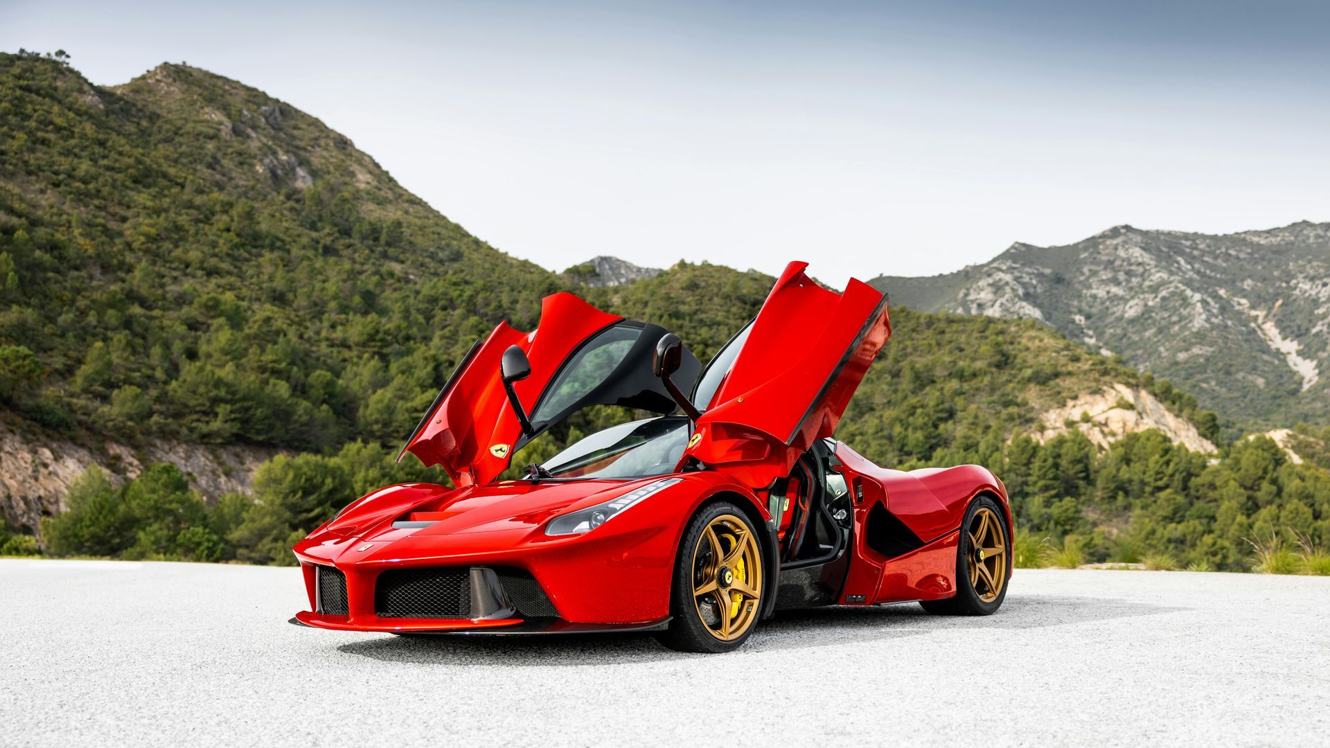 A red sports car is parked on the side of the road with its doors open.