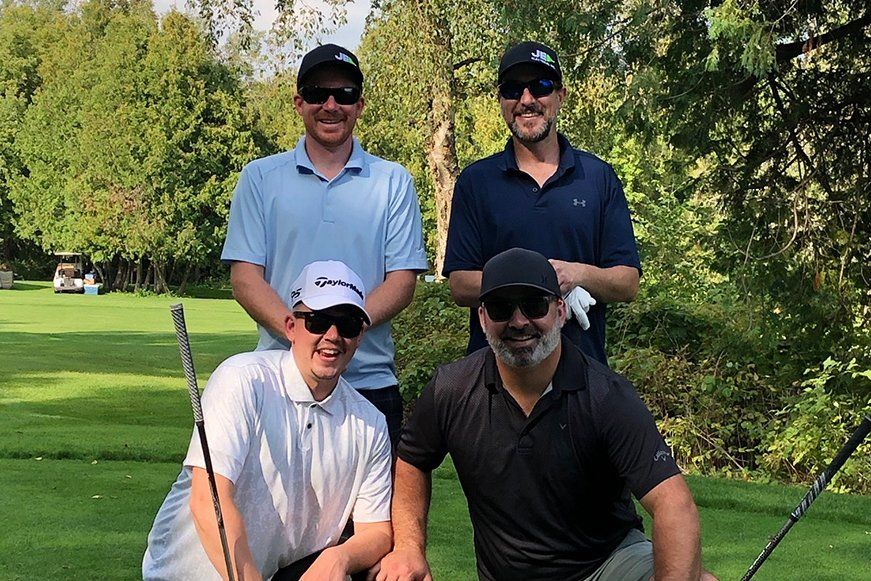 A group of men are posing for a picture on a golf course.