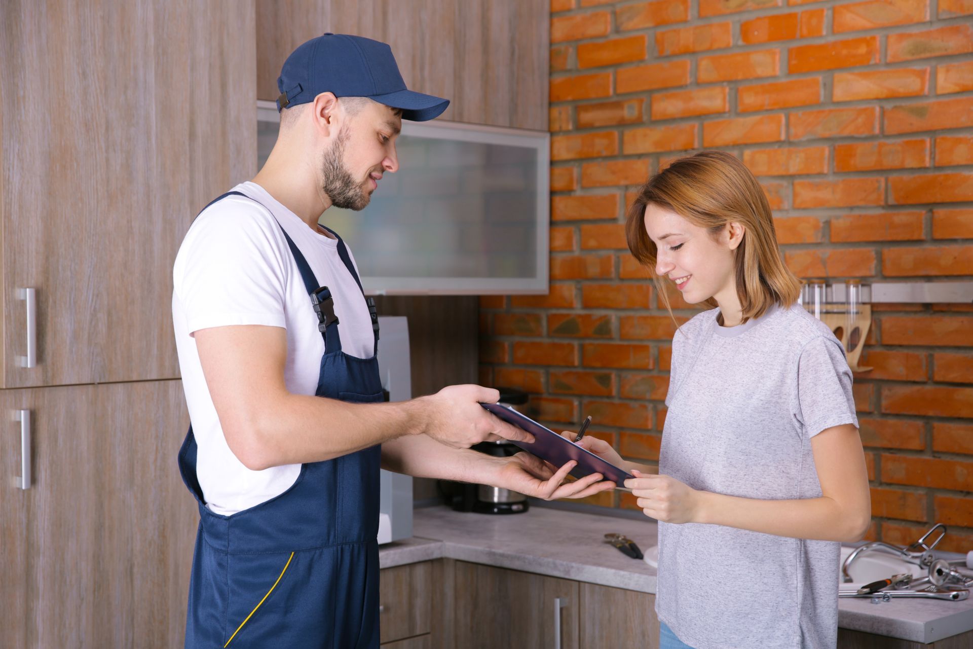 A man is giving a wallet to a woman in a kitchen.