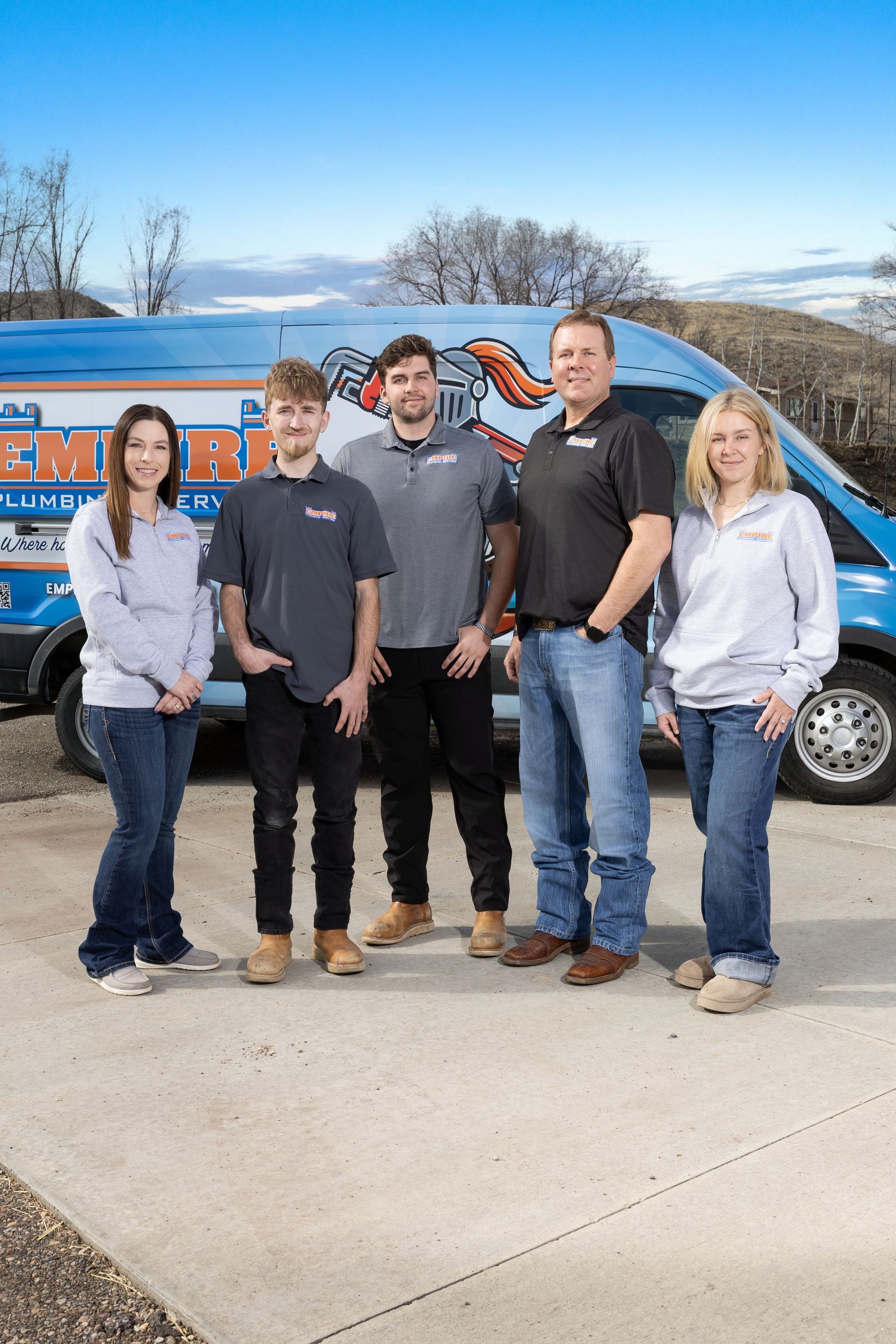 Five people standing in front of a blue van on a sunny day