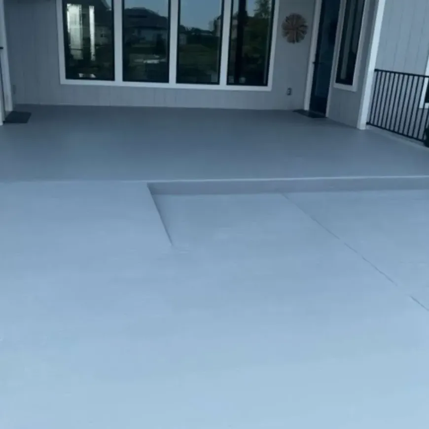 A gray concrete patio with a railing and a clock on the wall.