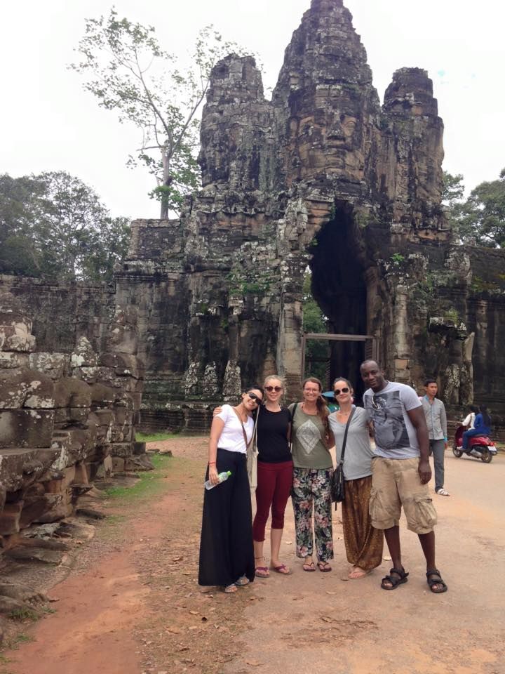 Group of people posing in front of an ancient stone archway in Cambodia.
