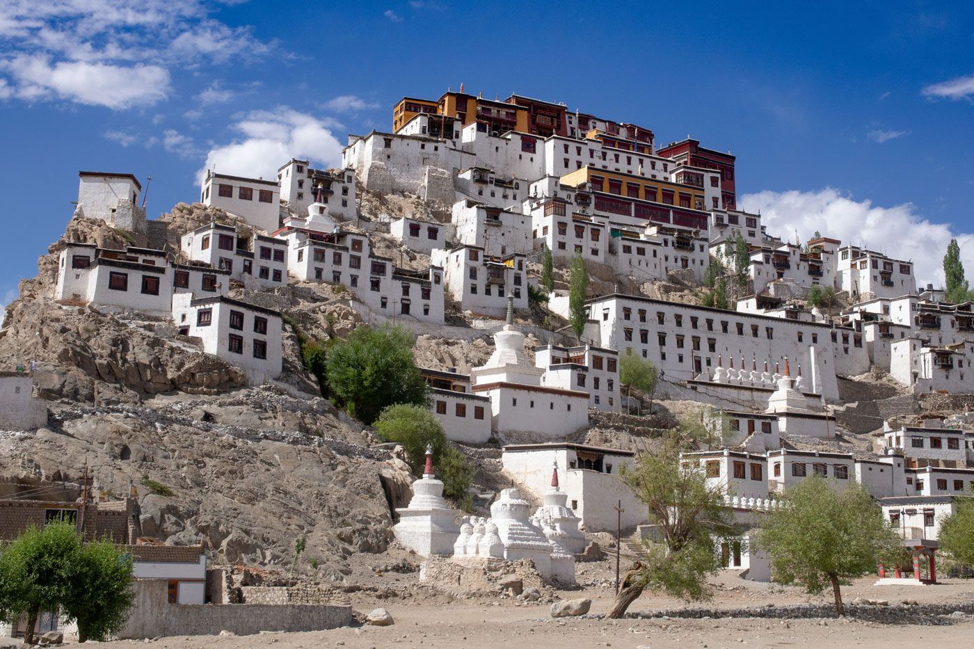 White monastery complex built on a rocky hillside under a blue sky.
