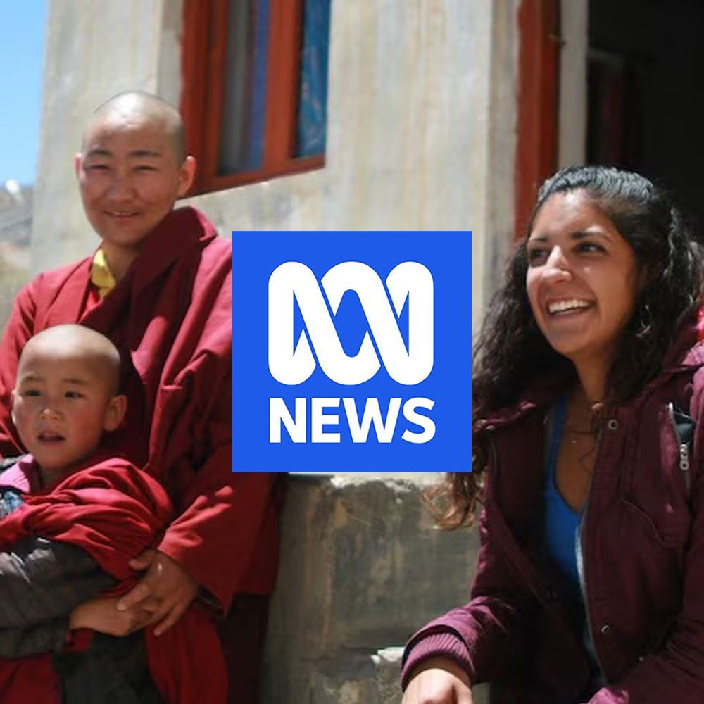 ABC News logo over a group of people: two monks, a child, and a woman smiling outdoors.