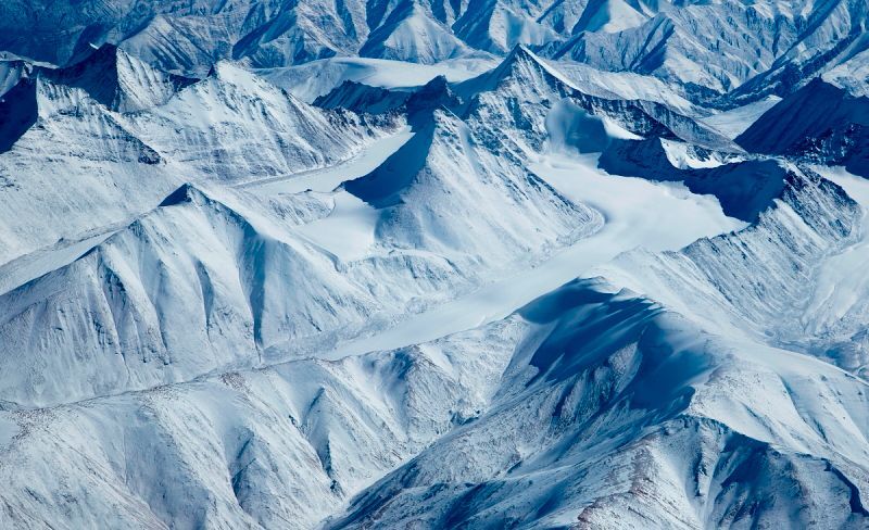 Snow-covered mountain range with ridged peaks, bathed in cool light.